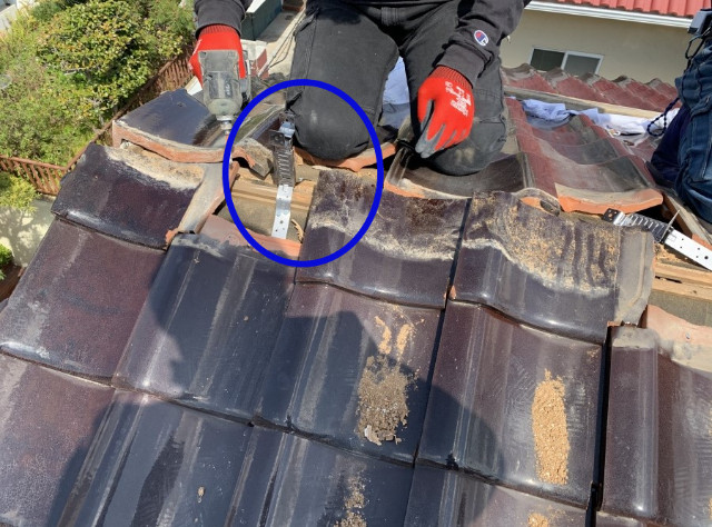 瓦屋根の棟に防災金具を施工する様子