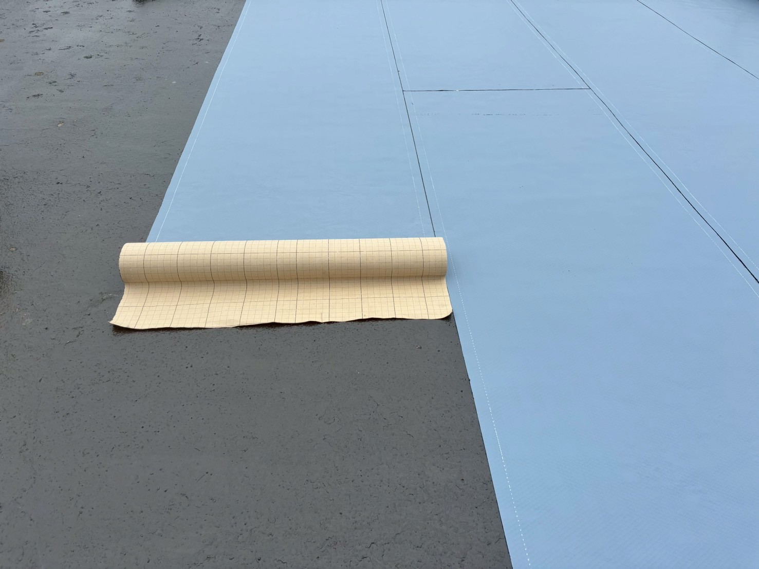 通気緩衝シート敷設中の写真 　「オルタックシートGSを貼り付けている作業中の様子。湿気を逃がす通気層を形成