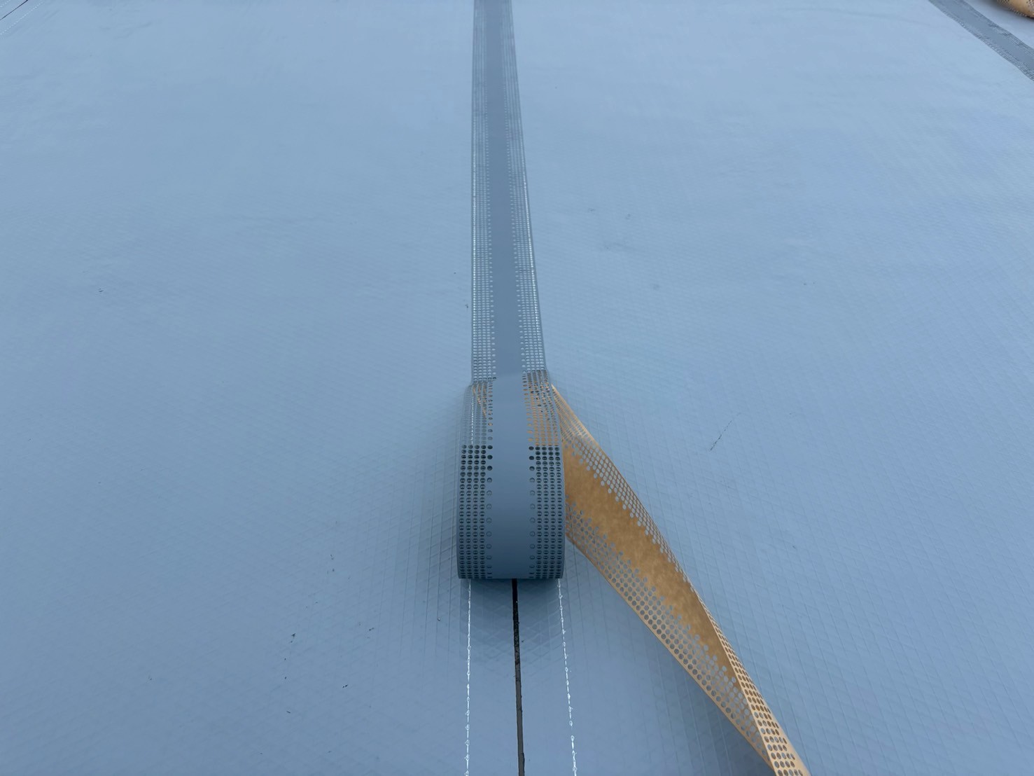 通気緩衝シート敷設中の写真 　「オルタックシートGSを貼り付けている作業中の様子。湿気を逃がす通気層を形成