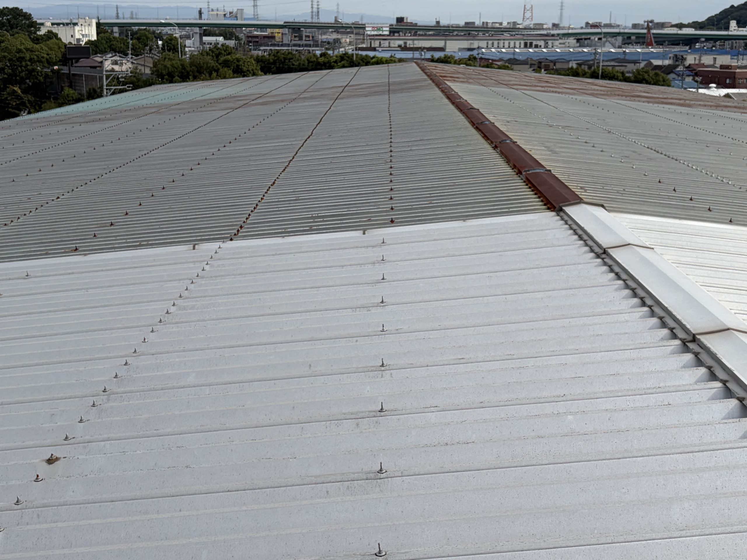 小牧市の大型物流倉庫で雨漏り調査を行った折板屋根。屋根全体に発生した錆と棟板金下の納まり不良を確認し、カバー工法をご提案