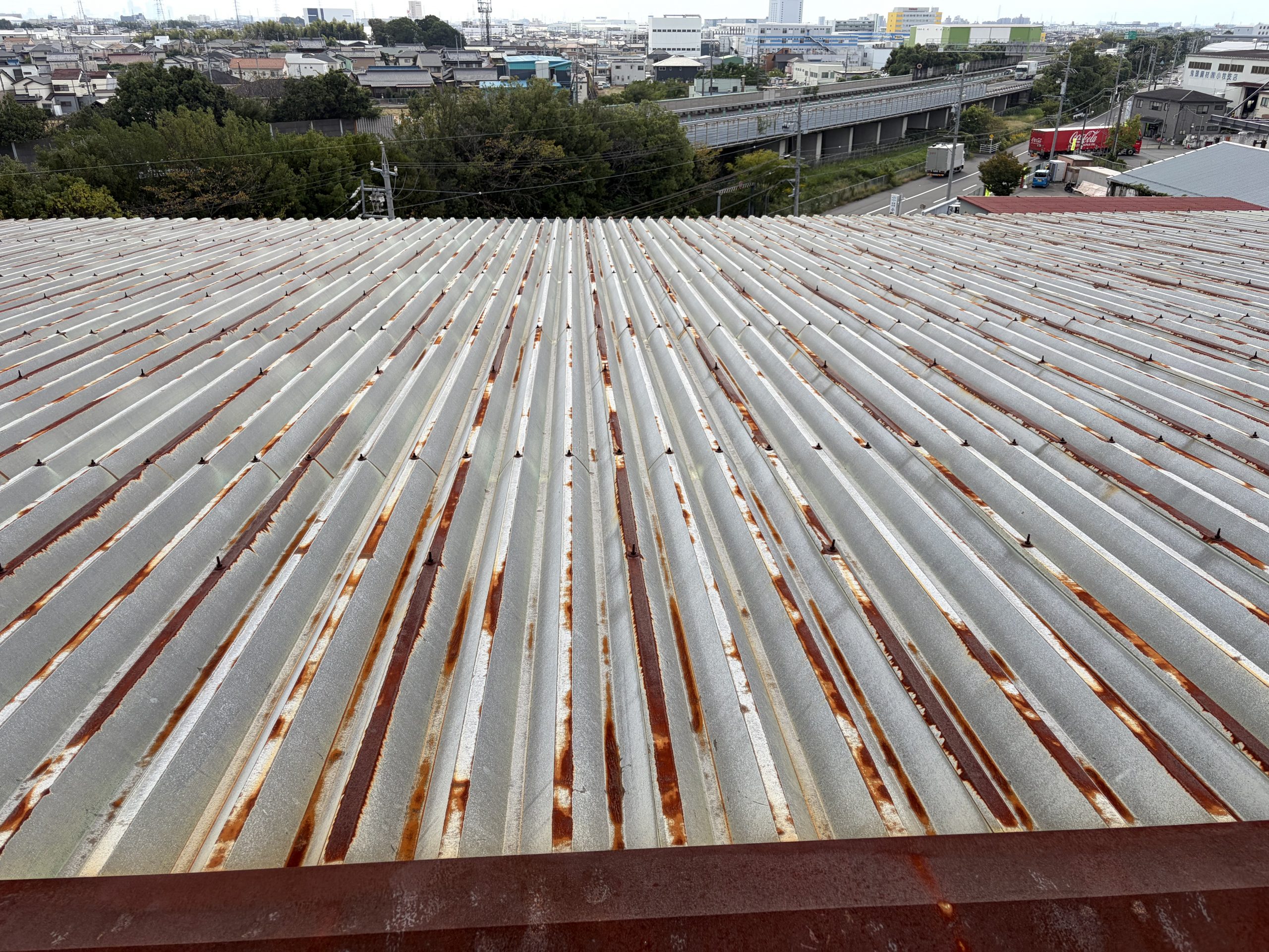 小牧市の大型物流倉庫で雨漏り調査を行った折板屋根。屋根全体に発生した錆と棟板金下の納まり不良を確認し、カバー工法をご提案