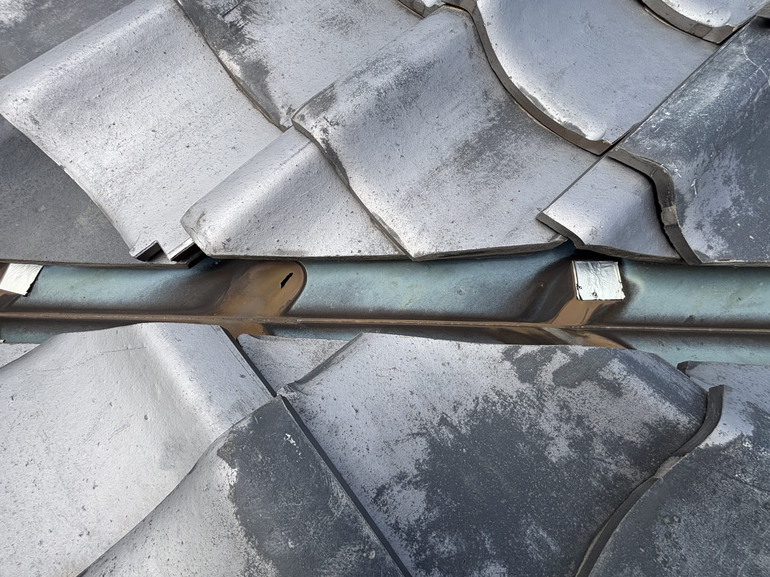 築40年経過したいぶし瓦屋根の谷樋に空いた穴の写真春日井市