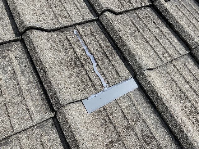 瓦の下に板金を差し込んでいる写真