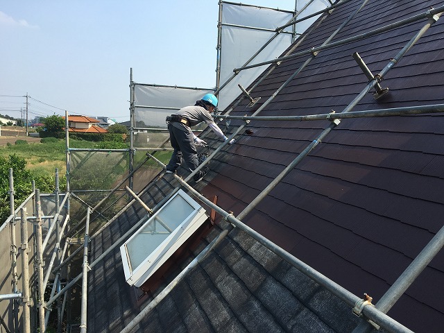 天窓ついている住宅の屋根で作業を行っている職人