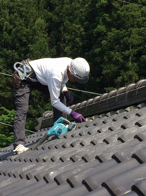 工具を使って瓦に付いた汚れを落としている作業員