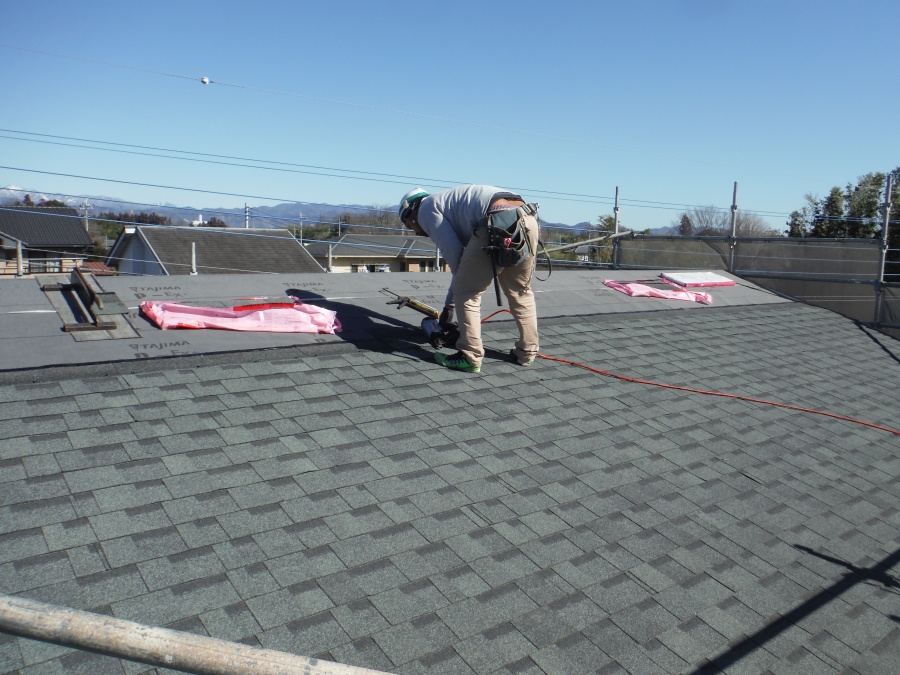 もう片方の屋根にも屋根材を専用のくぎ打ち機を使い貼っていく職人さんの写真