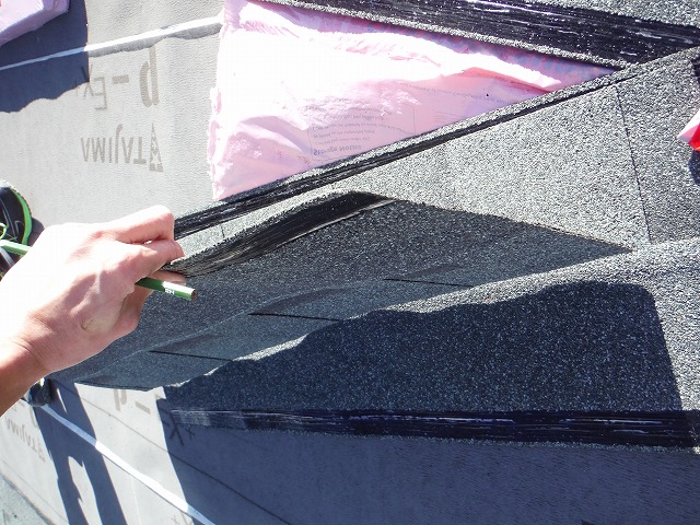 これから張る屋根材の裏に接着剤(黒色)を下準備として塗っている写真