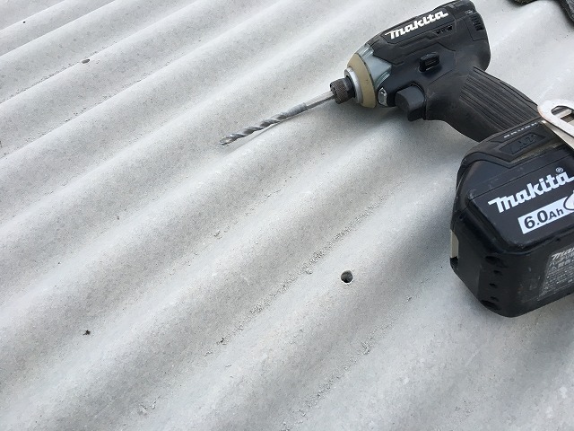 新しい波板を起き、止める為に穴を開けている風景