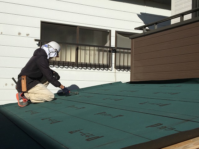 ルーフイング材を張っている作業員