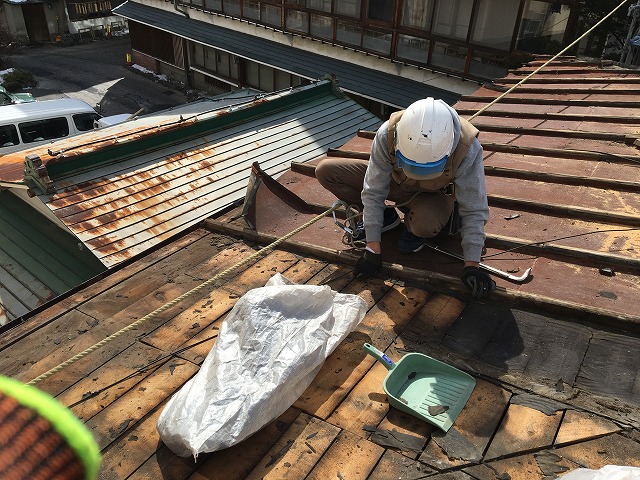 金属屋根の解体工事で古い防水紙を剥がす屋根屋さん