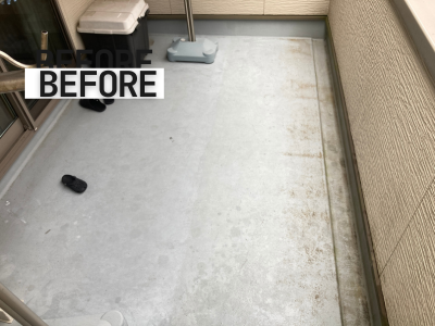 「排水まわりや角の部分のトップコートが剥がれ、黒ずみや劣化が進んだベランダの様子」  