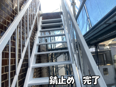 下地処理後の鉄骨階段に防錆塗料を均一に塗布し、腐食防止の膜を形成している塗装中の様子