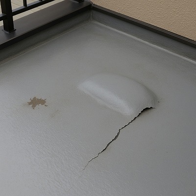 ベランダ防水層が内部の水分で膨れ上がり、浮きや剥がれが発生している状態を捉えた写真