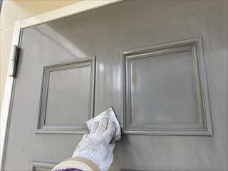 玄関扉の劣化した塗膜をケレン作業で除去している塗装工事の様子