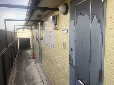 奈良市のハイツにて玄関ドア表面の塗装が剥がれ、めくれが発生している現場調査の様子