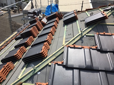 木の下地を組んだ屋根に瓦を並べる様子