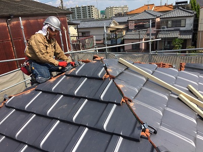 木の下地を組んだ屋根に瓦を並べる様子