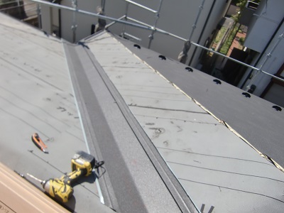 防水シートの上から金属の屋根材を被せていく様子