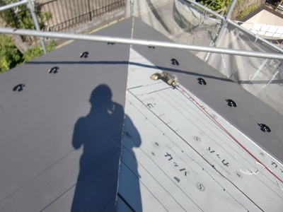 防水シートの上から金属の屋根材を被せていく様子