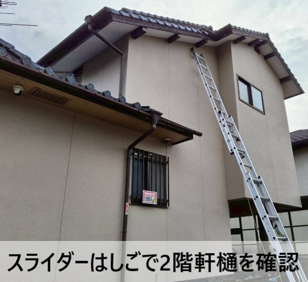 スライダーはしごで2階軒樋を確認している写真