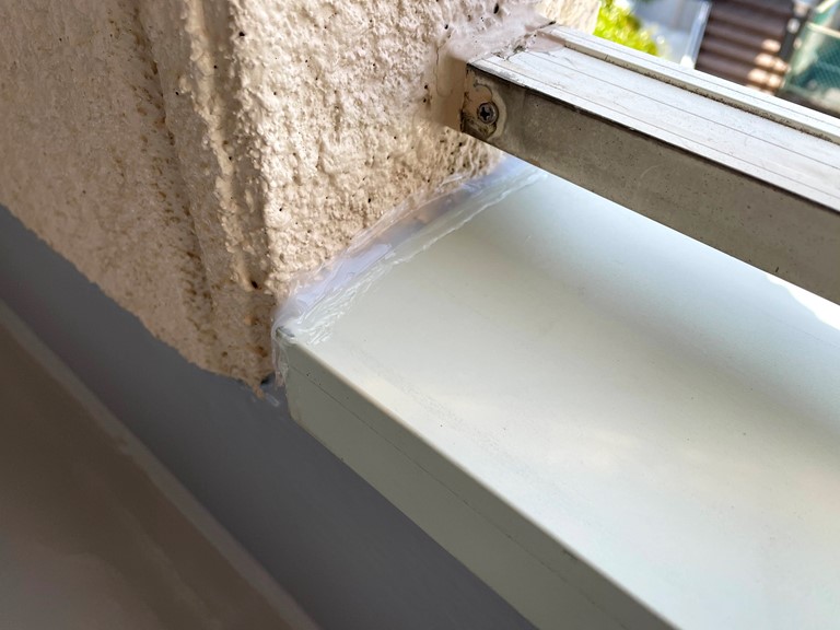 和歌山市でカラーステンレスの笠木を板金職人が設置し、ALC版と笠木の両サイドの継ぎ目に雨水が侵入しないようコーキングを充填しておきます