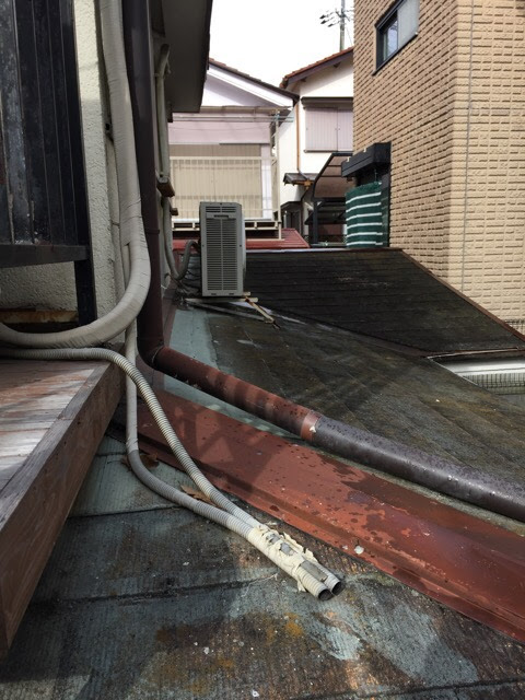  屋根上のエアコン室外機周辺。板金（金属部分）にサビが発生し、カラーベスト屋根全体が色あせ・コケで傷んでいる様子（大阪市平野区）