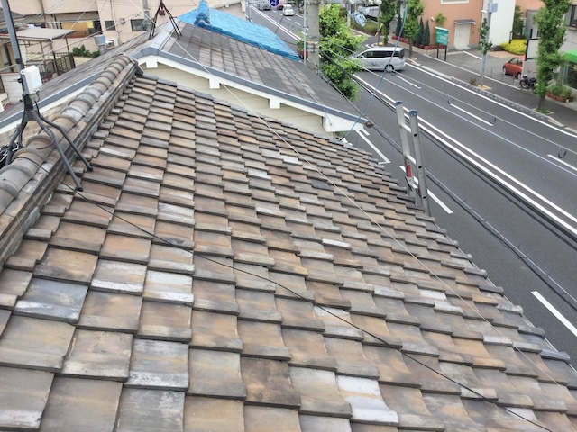 八尾市の屋根全景。波打つ瓦と全体的な経年劣化の様子。