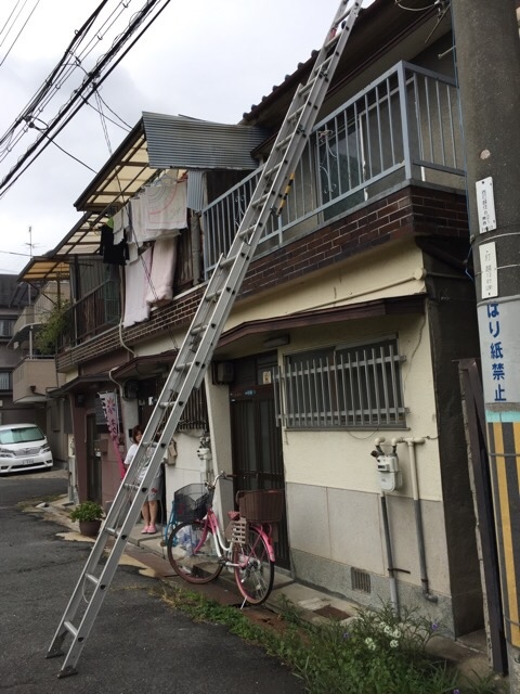 八尾市志紀町の2階ベランダへハシゴをかけて現地調査を行う様子