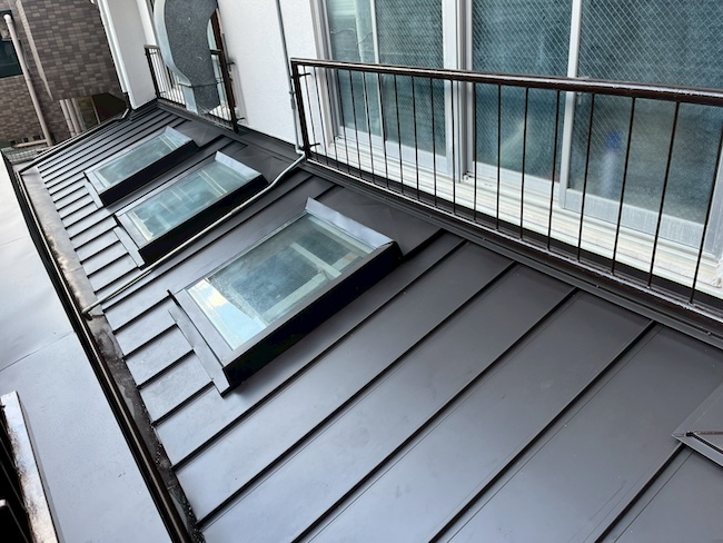 カバー工法による金属屋根リフォーム完工。天窓周りの複雑な板金も美しく納まり、雨漏りの不安を完全に解消した全景写真。