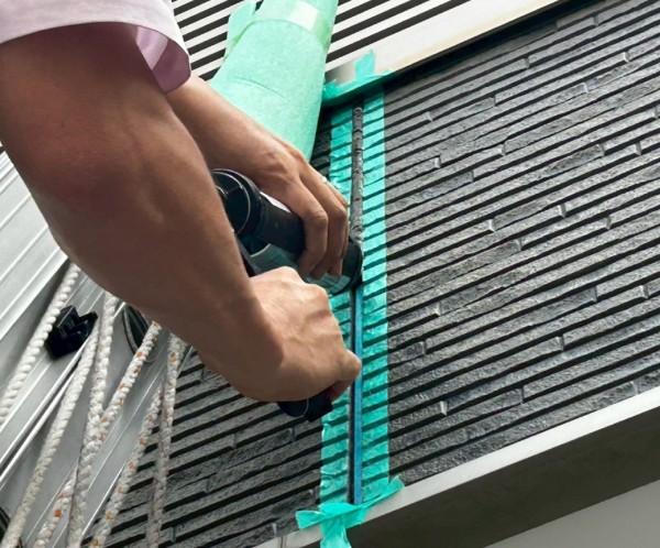 コーキングガンで目地シーリングを充填している