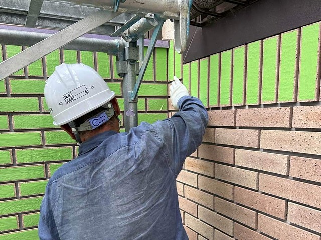 乾式タイル目地込み工事でタイル本体に養生テープをあり付けている職人