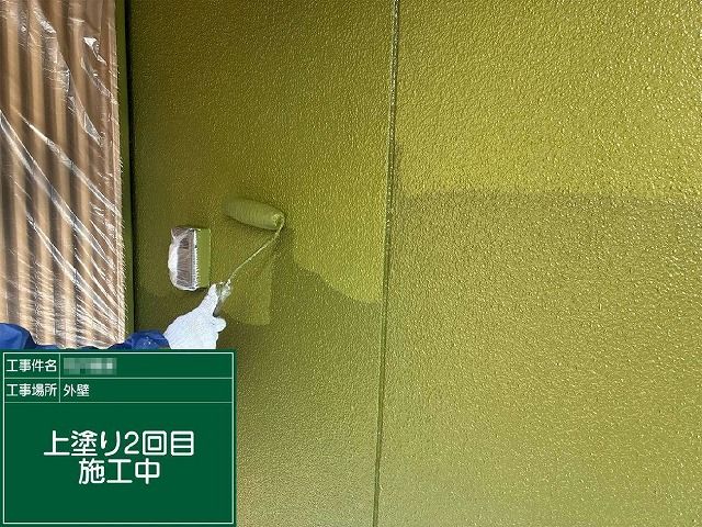 モルタル外壁工事の上塗りをローラーで塗り進めている施工中の様子