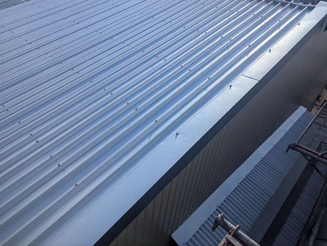 倉庫屋根カバー工事のケラバ板金を専用ビスで固定している状況