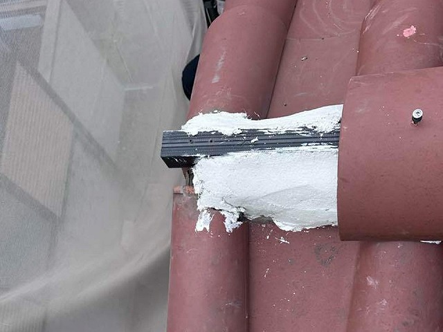 棟瓦取り直し工事の新たに設けた土台部へ冠瓦を設置している様子