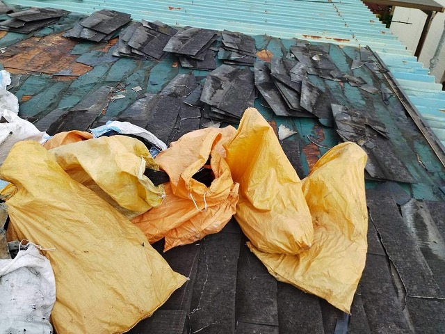 スレート屋根を解体してゴミ袋に詰めている様子