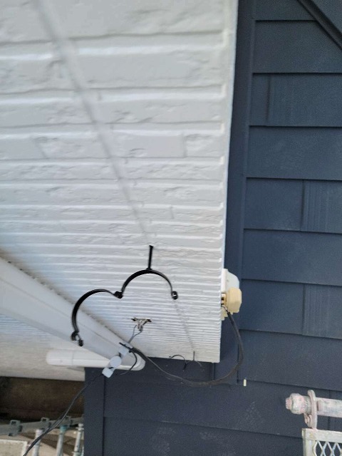 塗り替えをした外壁サイディングに竪樋取り付け金具を設置