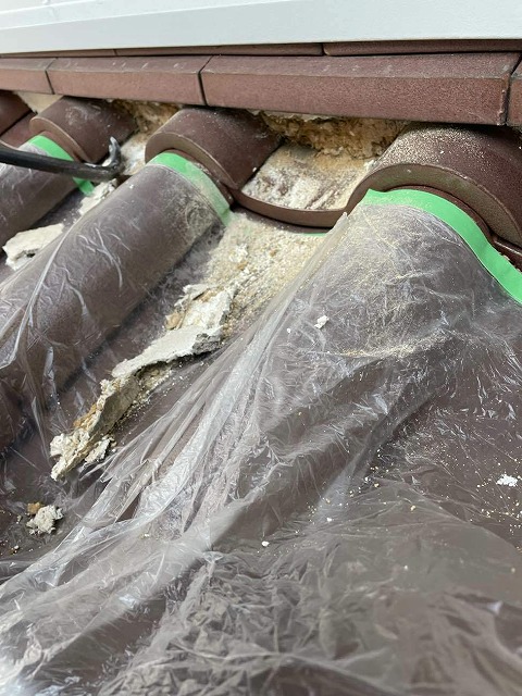 マスカー養生して下屋根の漆喰を除去している様子