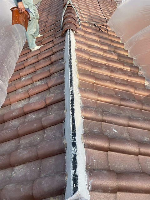 樹脂製の垂木と漆喰でつくった土台に上に棟瓦を被せていく様子