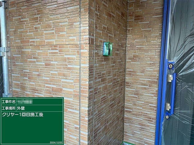 石目調サイディング外壁に対するクリヤー塗装1回目が完了した状況