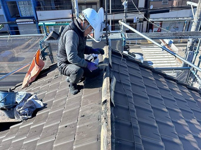 棟瓦取り直し工事で既存漆喰の撤去を行う屋根職人