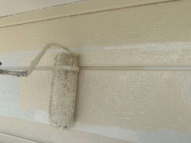 金属サイディングへの仕上げ塗装を行っている様子