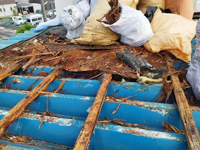 スレート屋根の防水シートや木下地を解体してゴミ袋に詰めている様子