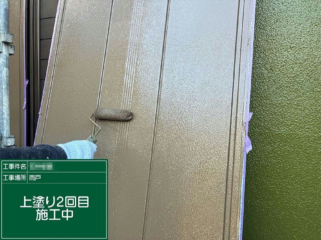 雨戸にローラーで上塗り2回目を塗り重ねている施工中の様子