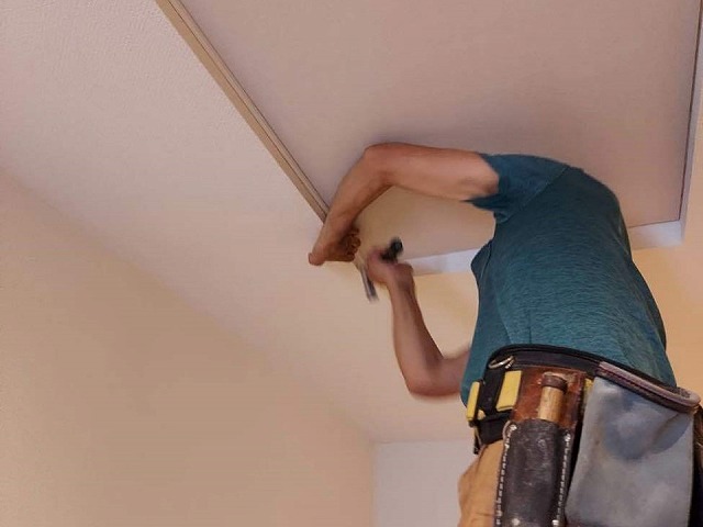 化粧ボードを壁との継ぎ目部分に見切りを取り付けている様子