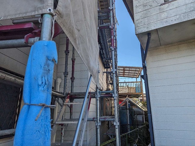 足場の支柱にクッション養生を施している様子