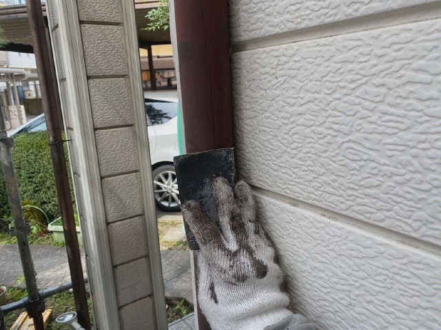 塗装メンテナンスで竪樋に目荒らしを行っている様子