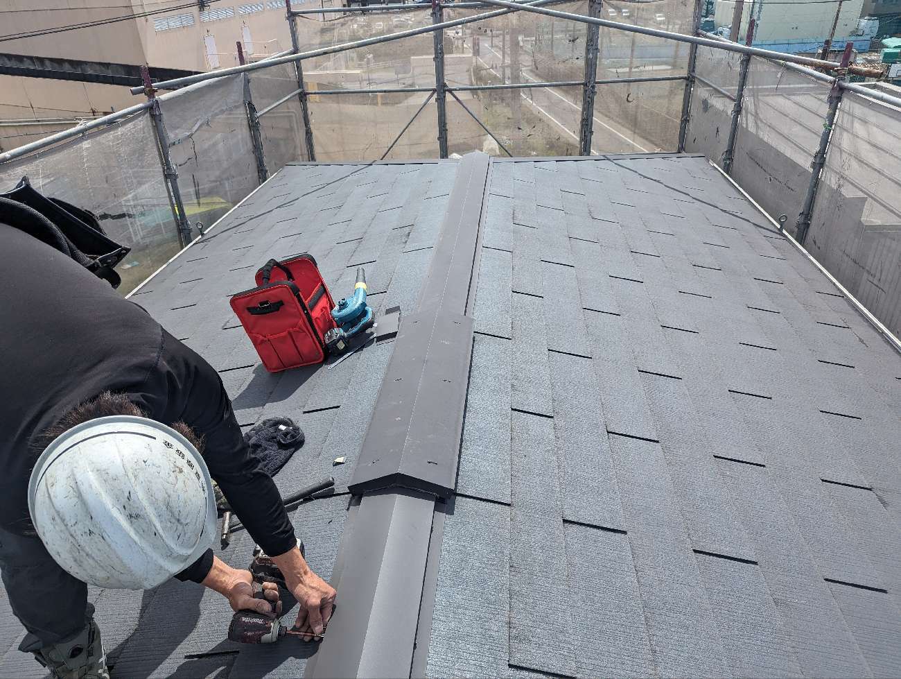 ステンレスビスで棟板金をつけ直す様子