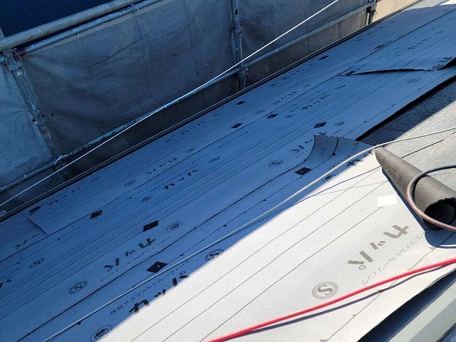 屋根カバー工法で軒先から棟に向かって防水シート貼り施工