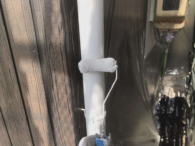 竪樋にローラーで塗装を行う塗装工