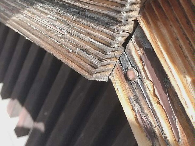 表面塗装が剥がれて激しく傷んでいる木製の破風